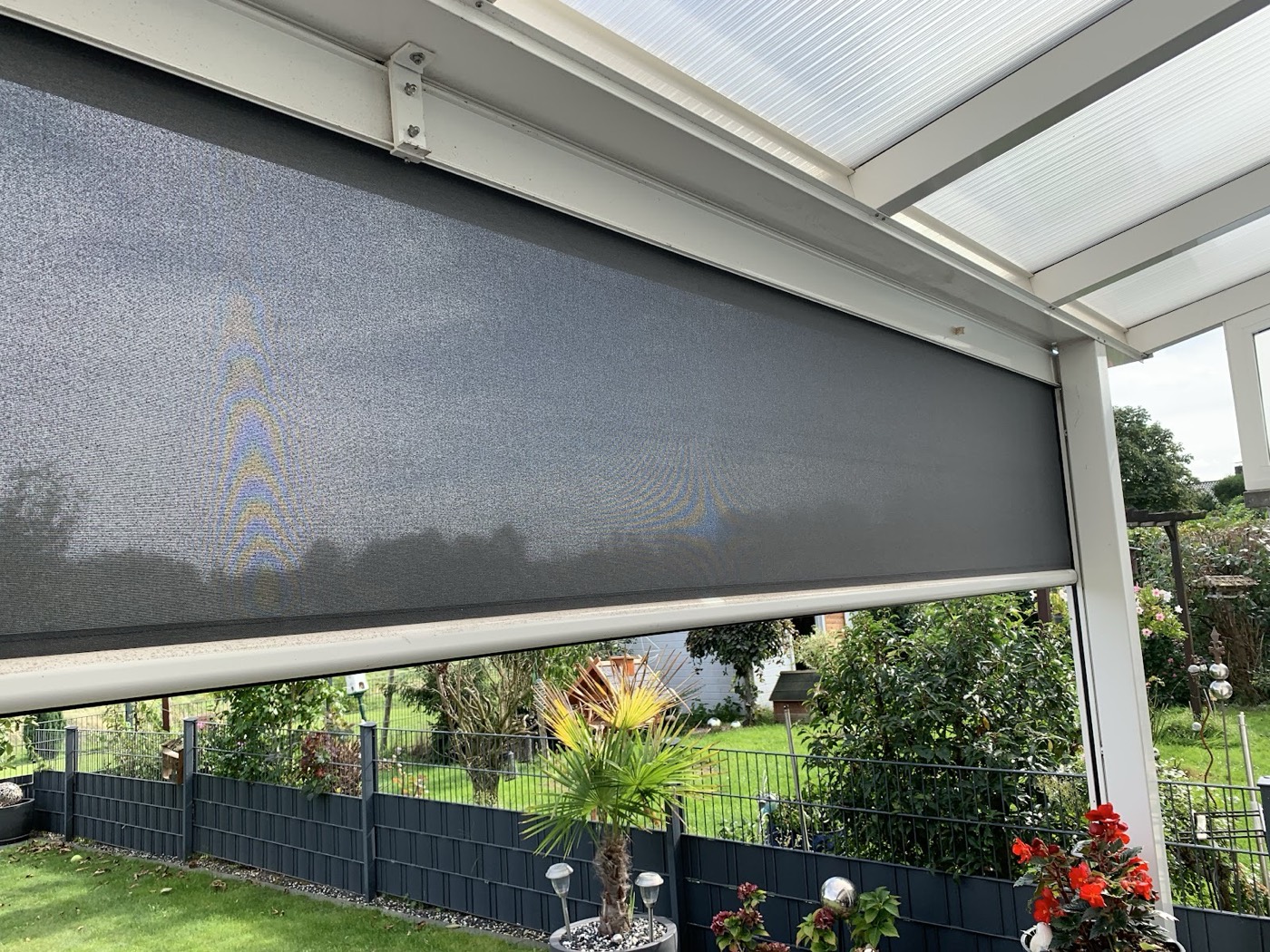 Grauer senkrechter Sonnenschutz an einer Terrasse mit Blick in den Garten