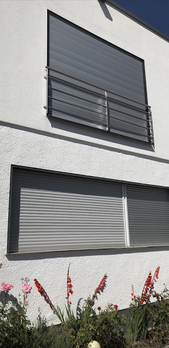 Grauer Rollladen an einer hellen Hausfassade