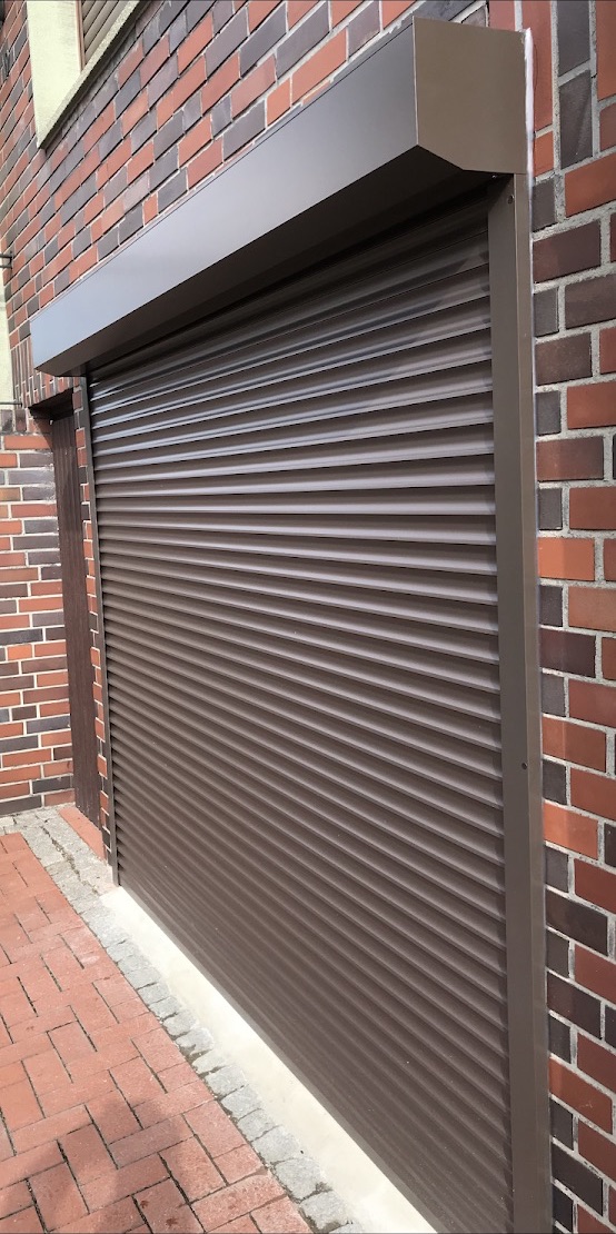 Dunkler Rollladen neben einer Backsteinwand