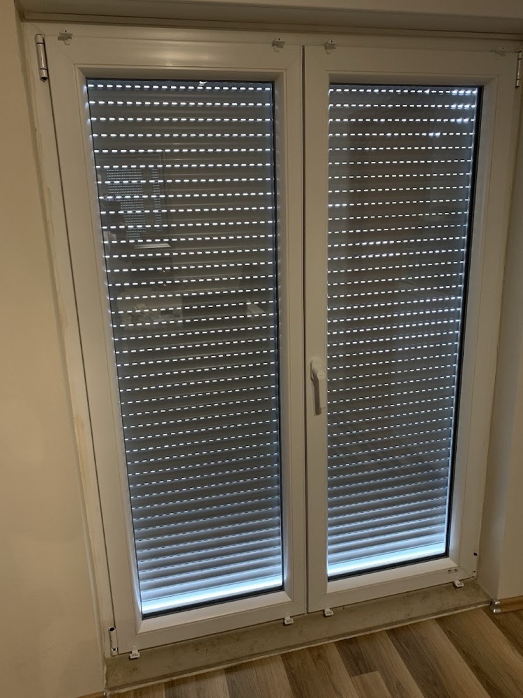 Rollladen von innen an einem weißen Fenster, Licht scheint durch die Lamellen