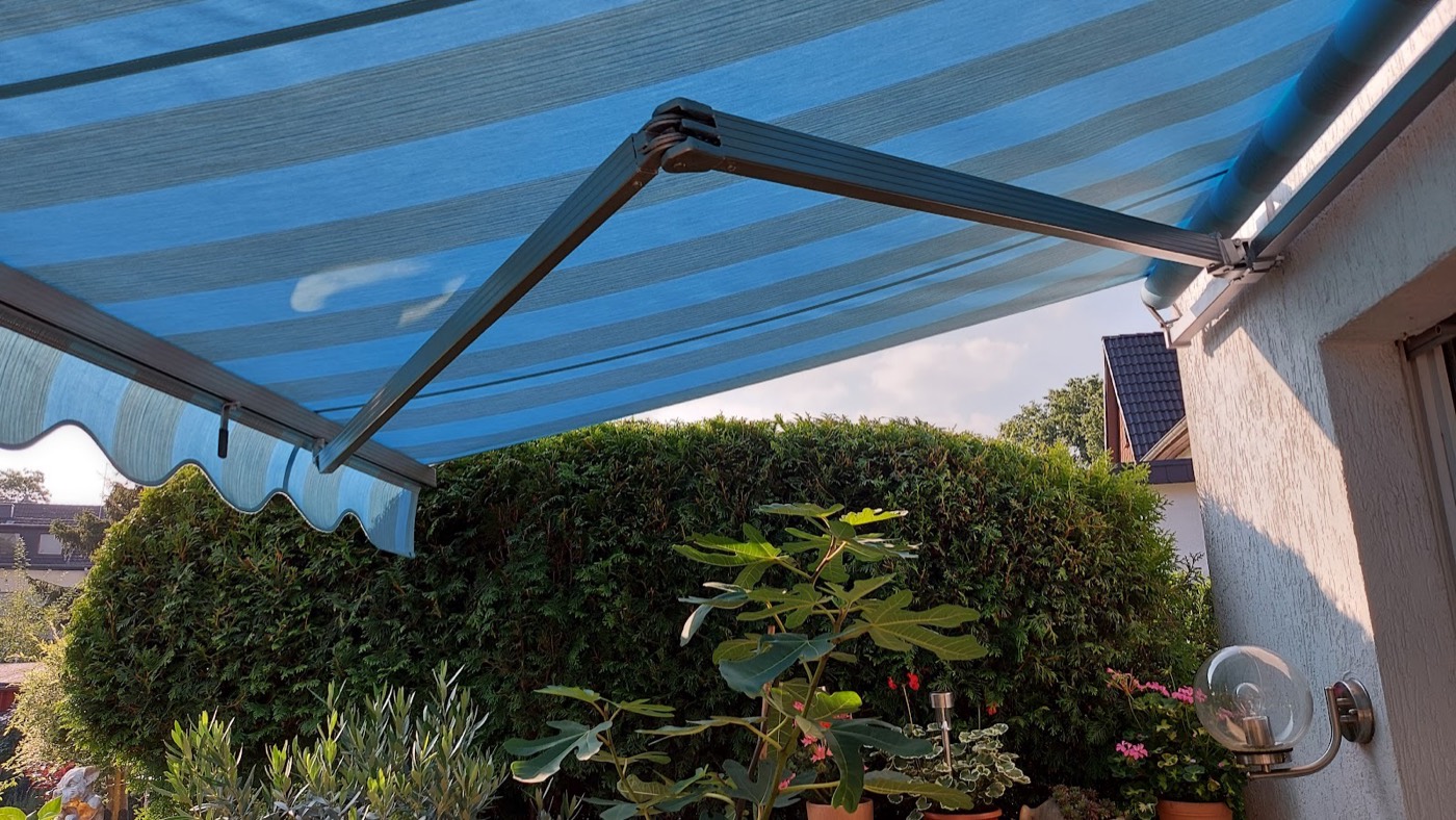 Blaue Markise über einer Terrasse mit Pflanzen